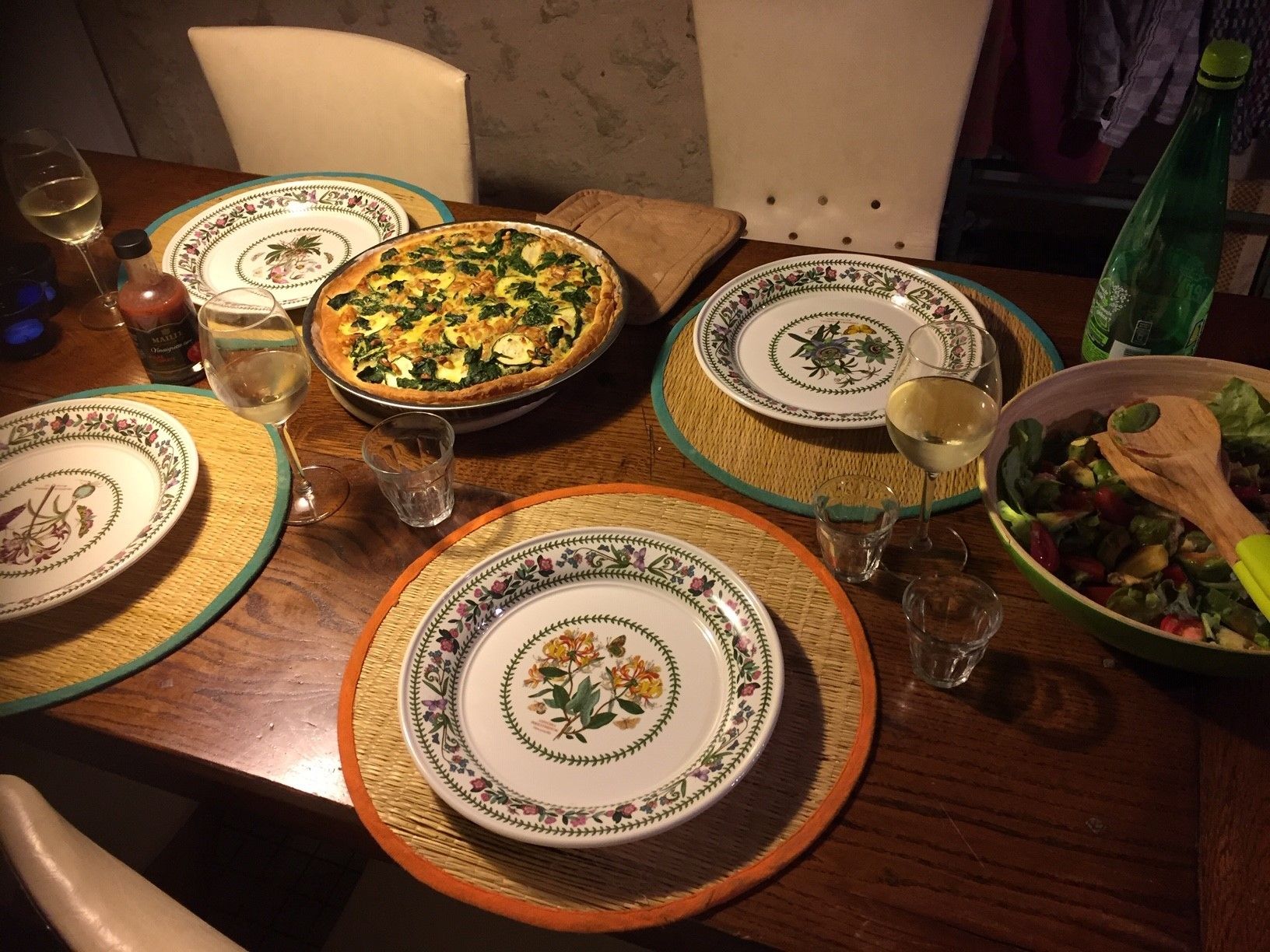 Een eettafel gedekt met borden, glazen, een taart en een saladeschaal.