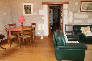 A room with a dining table, chairs, a green leather sofa, and a doorway leading to another room. - Holiday Home 'Les Indeaux' with Private Pool, Private Terrace and Wi-Fi (Lusignac)