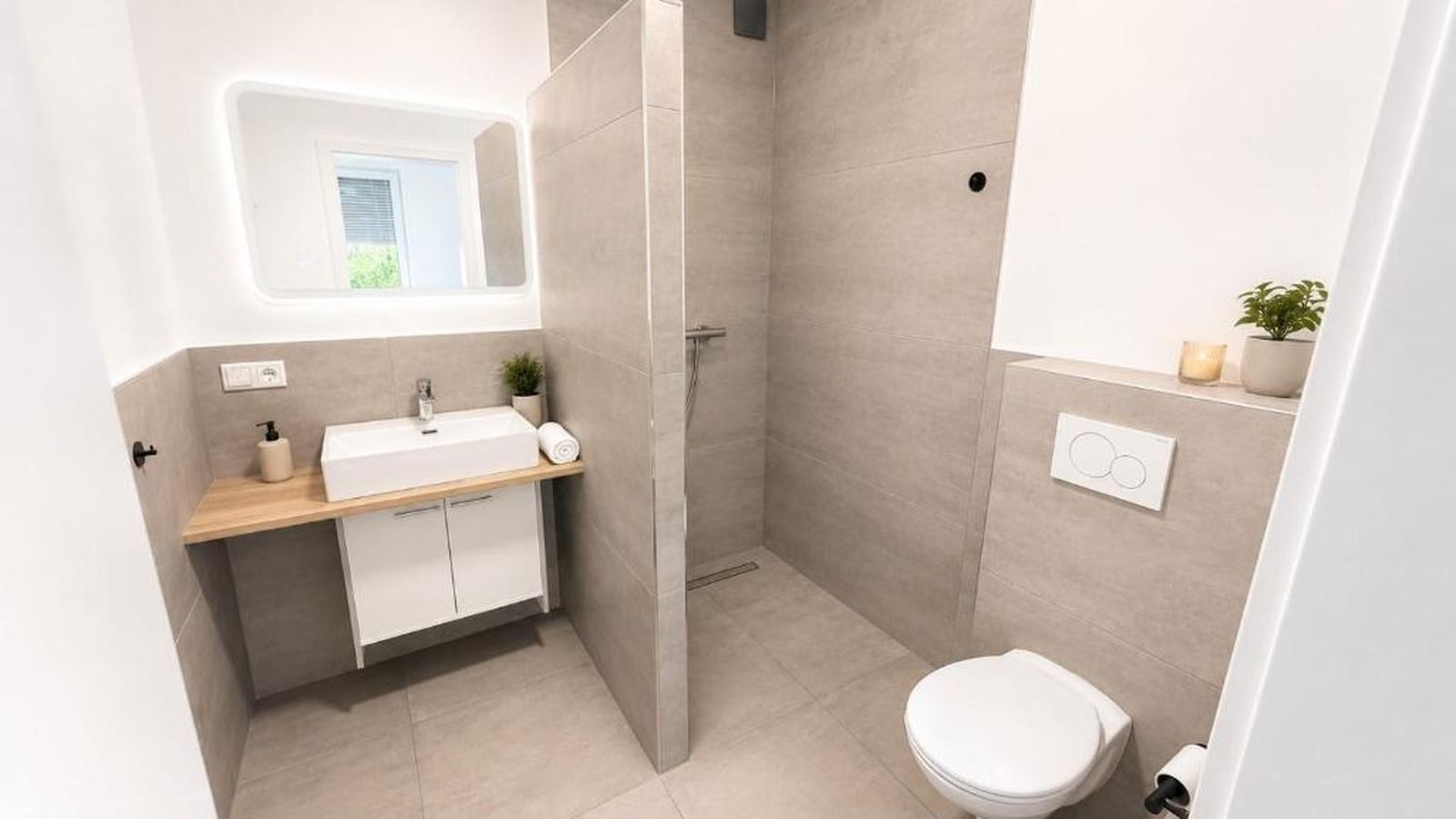 A modern bathroom with a shower, toilet, and sink.