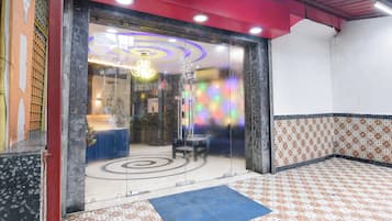 Um saguão de hotel com balcão de recepção, área de estar e piso estampado.