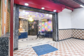 Un vestíbulo de hotel con mostrador de recepción, zona de estar y suelo estampado.