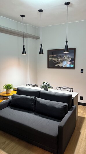 A modern living room with a sofa, dining table, and pendant lights. - New Listing (Rio de Janeiro)