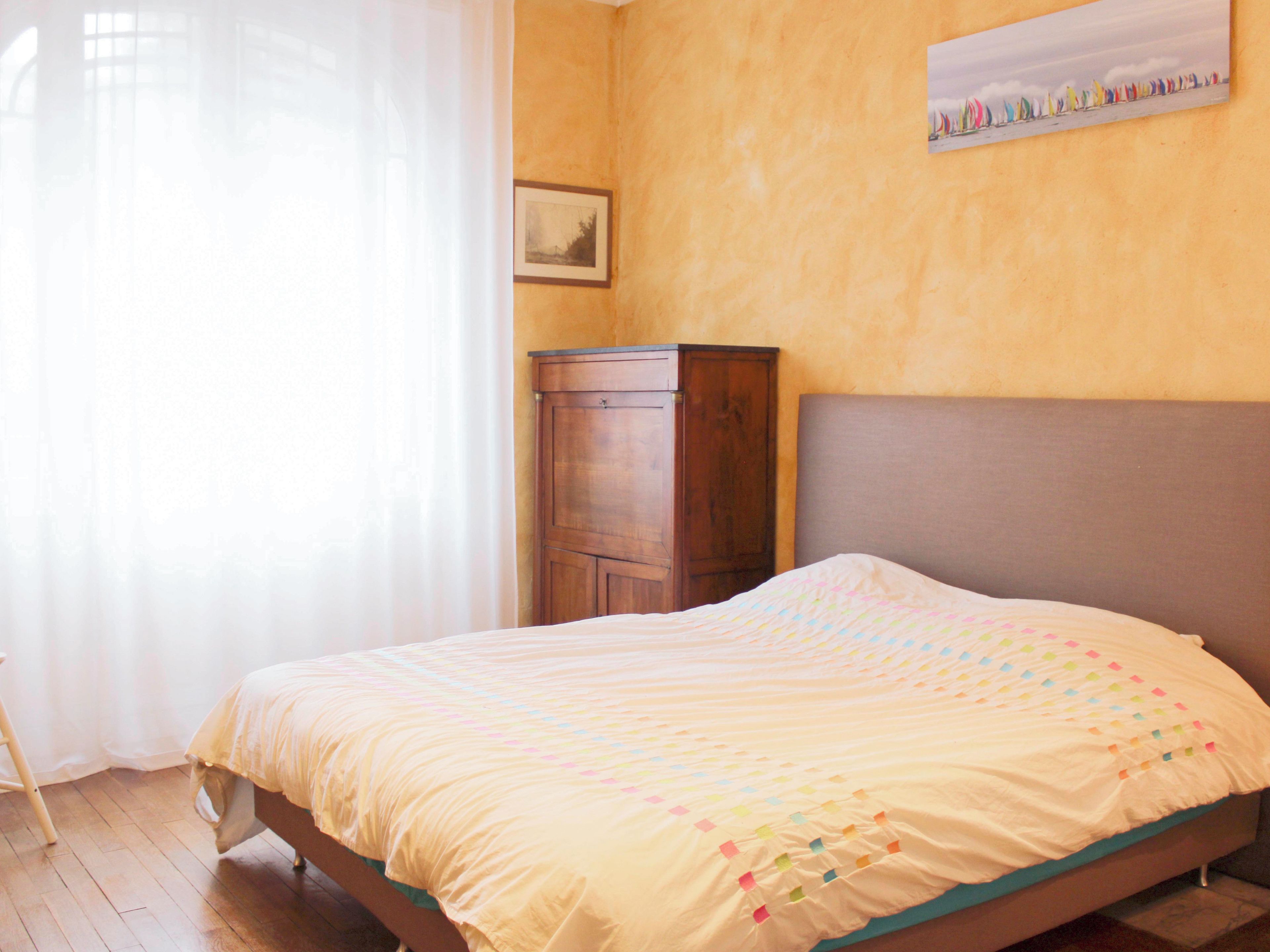 Un dormitorio con una cama, un armario de madera y un cuadro en la pared.