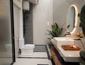 Een moderne badkamer met toilet, douche, wastafel en spiegel.