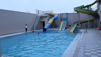 Une piscine dotée de plusieurs toboggans et d’une échelle menant à une zone abritée.