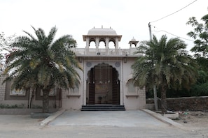 A traditional building with a central archway, a small dome on top, and a balcony with railings. - Indraprastha Resort (Barmer Gadan)