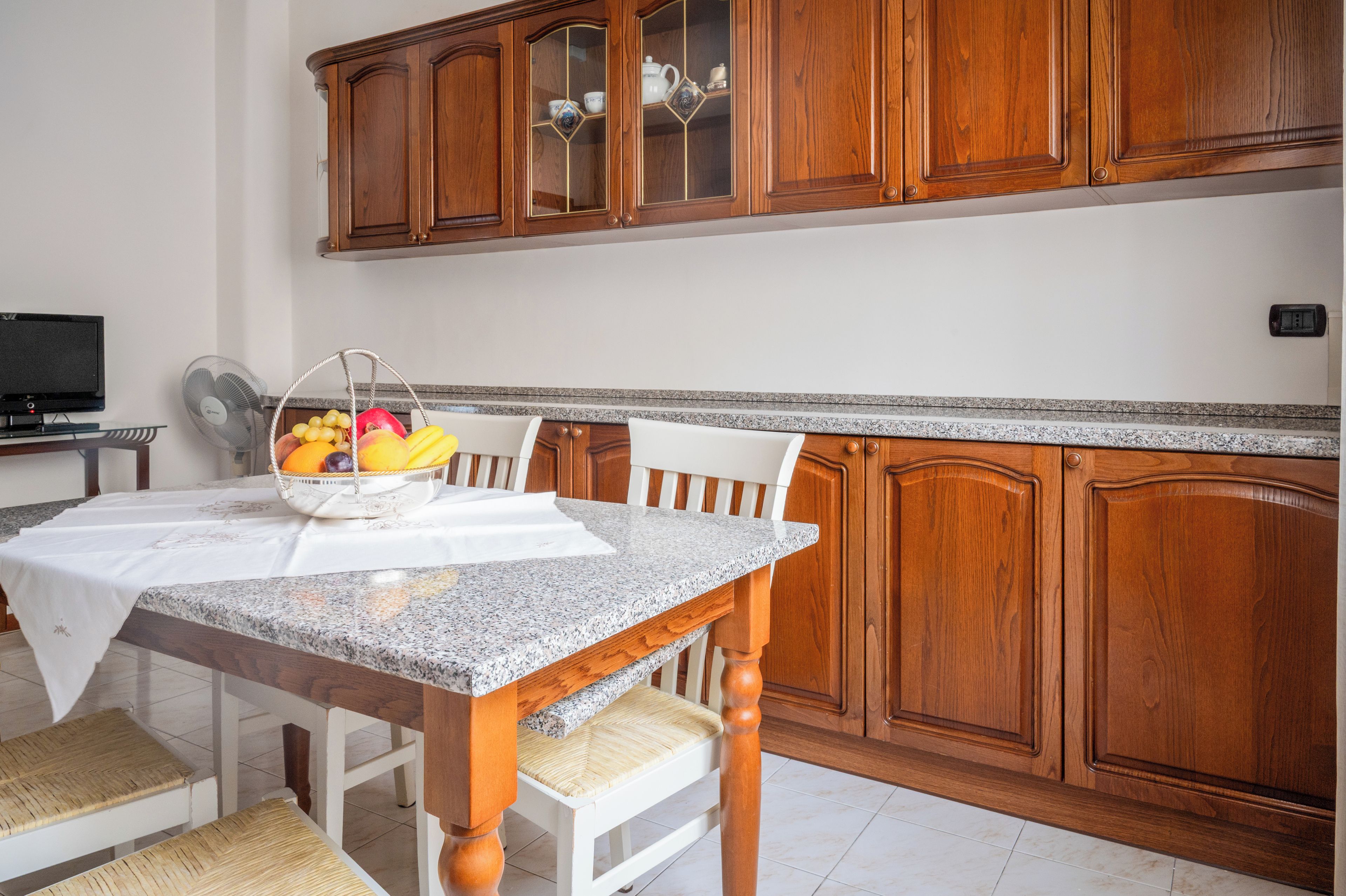 Cozinha com armários de madeira, bancada de granito e mesa de jantar com cadeiras.