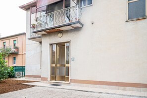 Um edifício com entrada no andar térreo, uma varanda com grades de metal e uma janela com porta.