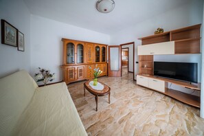 A living room with a sofa, a TV stand, a wooden cabinet, and a marble floor. - Casa Valeria (Ancona)