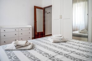 Quarto com cama, penteadeira, guarda-roupa e espelho.