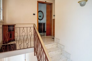 A staircase with a marble floor leading to a room with a wooden door and a mirror. - Casa Valeria (Ancona)