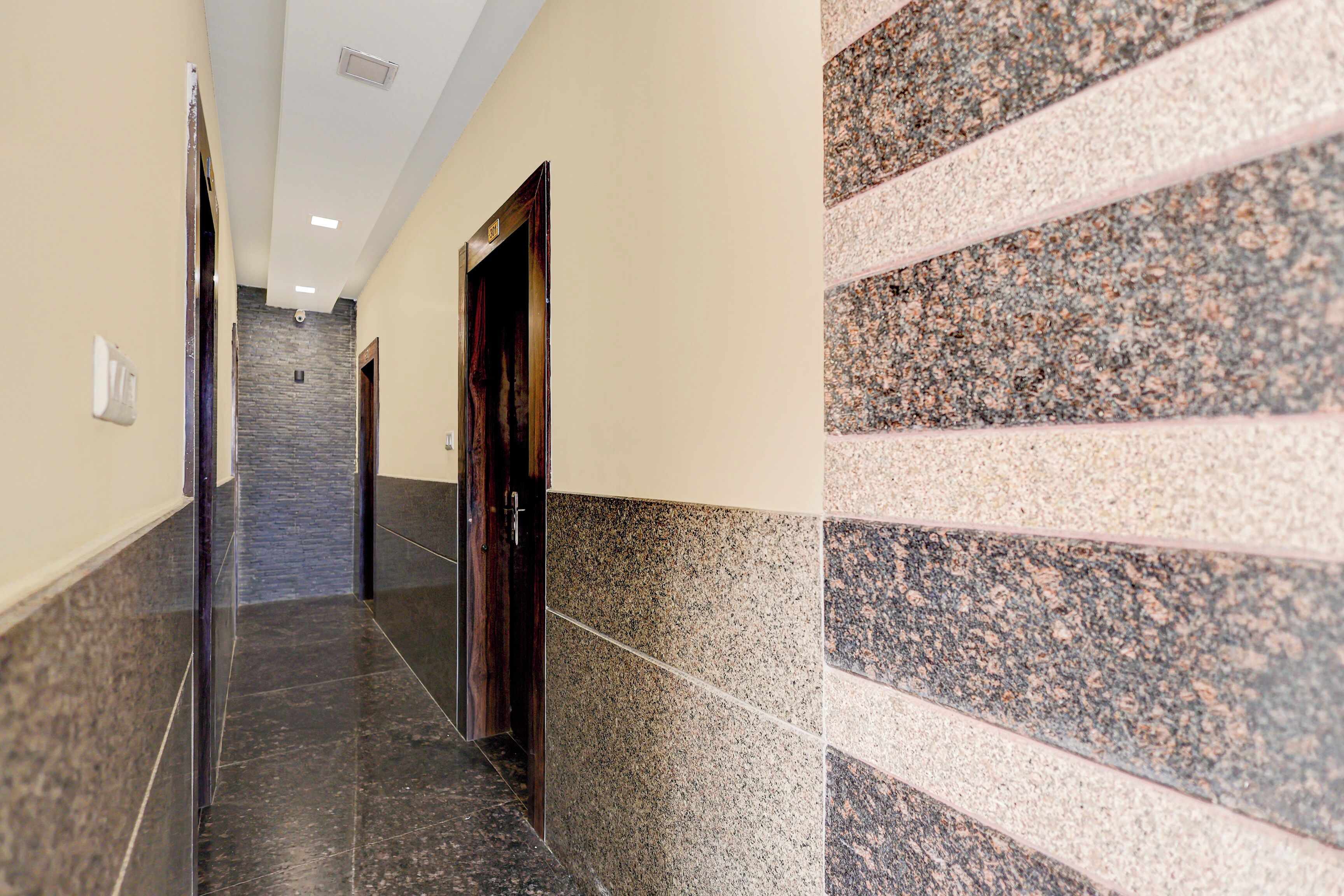 Un pasillo con piso de mármol, una puerta de madera y una pared con diseño similar al granito.