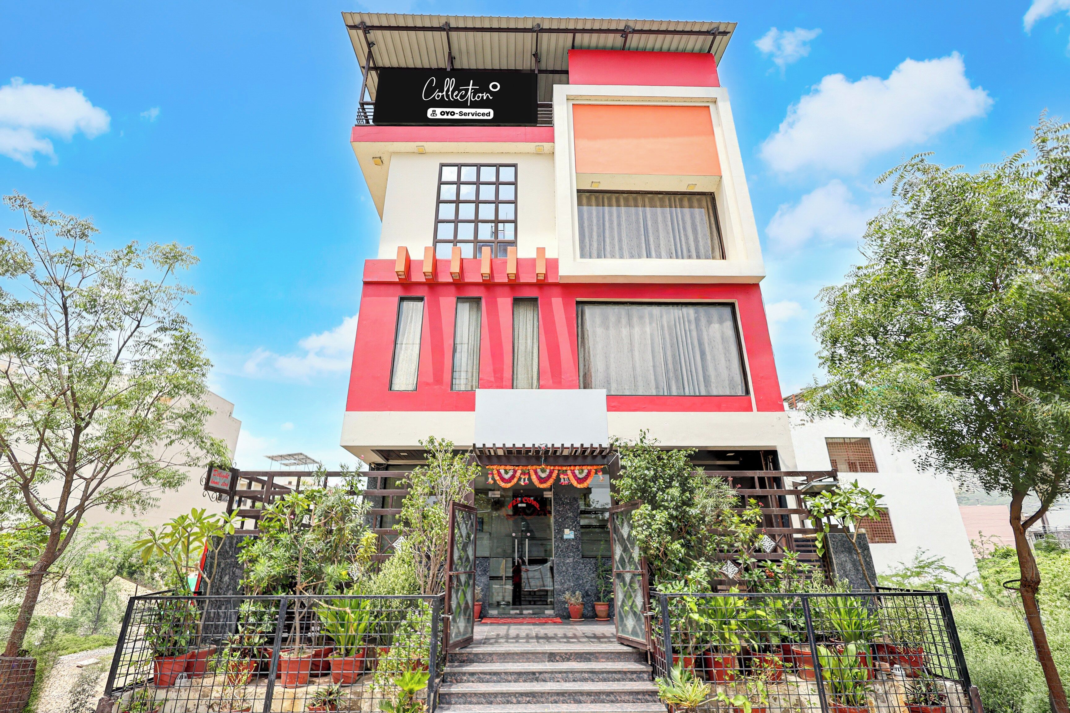 Un edificio de varios pisos con fachada roja y blanca, una entrada visible con escalones y un letrero que indica que cuenta con servicios de OYO.