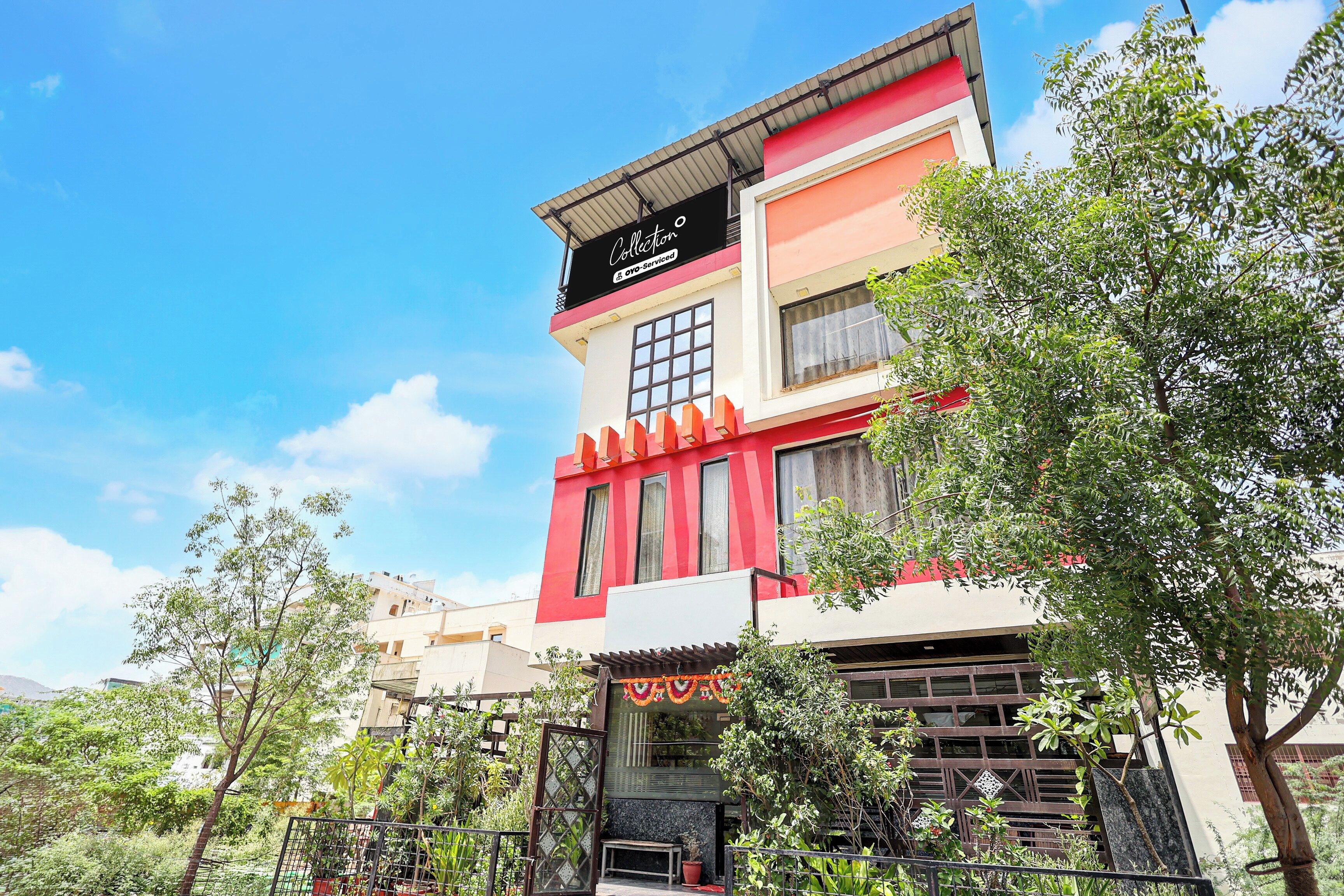 Un edificio de varios pisos con fachada roja y blanca, un letrero visible que dice 'Collection & Oyo-Service', y una entrada con portón.
