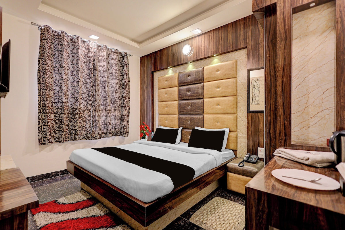 A modern hotel room with a large bed, a bedside table, a mirror, and a bathroom.