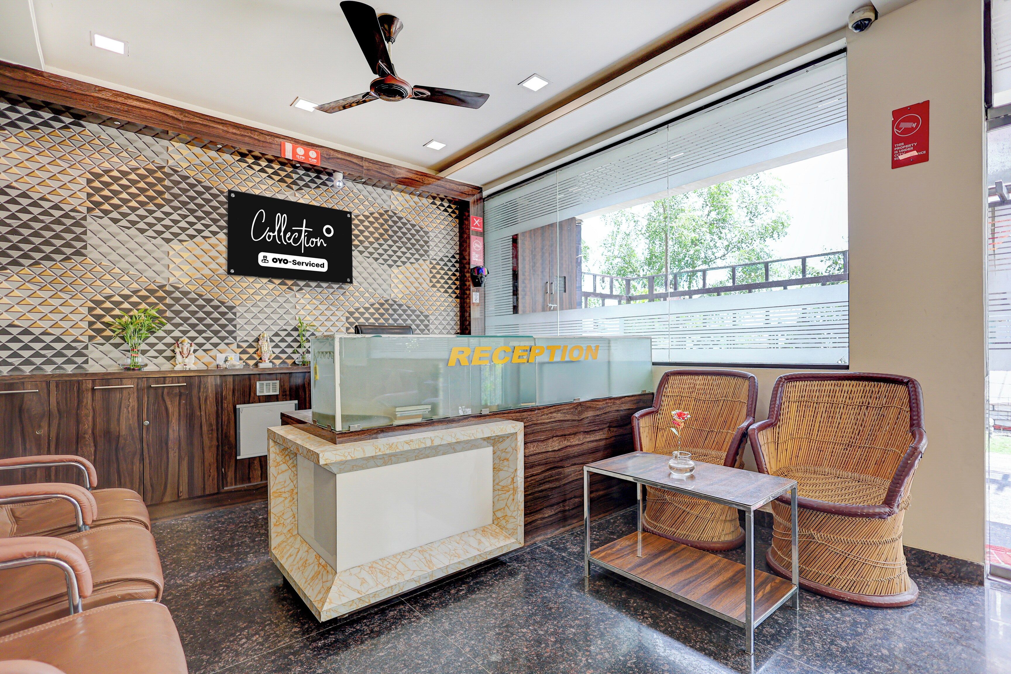 Un área de recepción con mostrador, asientos, un ventilador de techo y una pared con diseño.