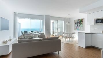 Un espai modern d'estar amb sofà, taula de menjador i zona de cuina.