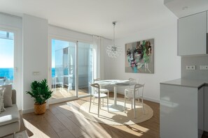 Una sala de estar moderna con comedor, un ventanal y vista al mar.