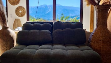 Quarto com cama grande, duas janelas e vista para montanhas.