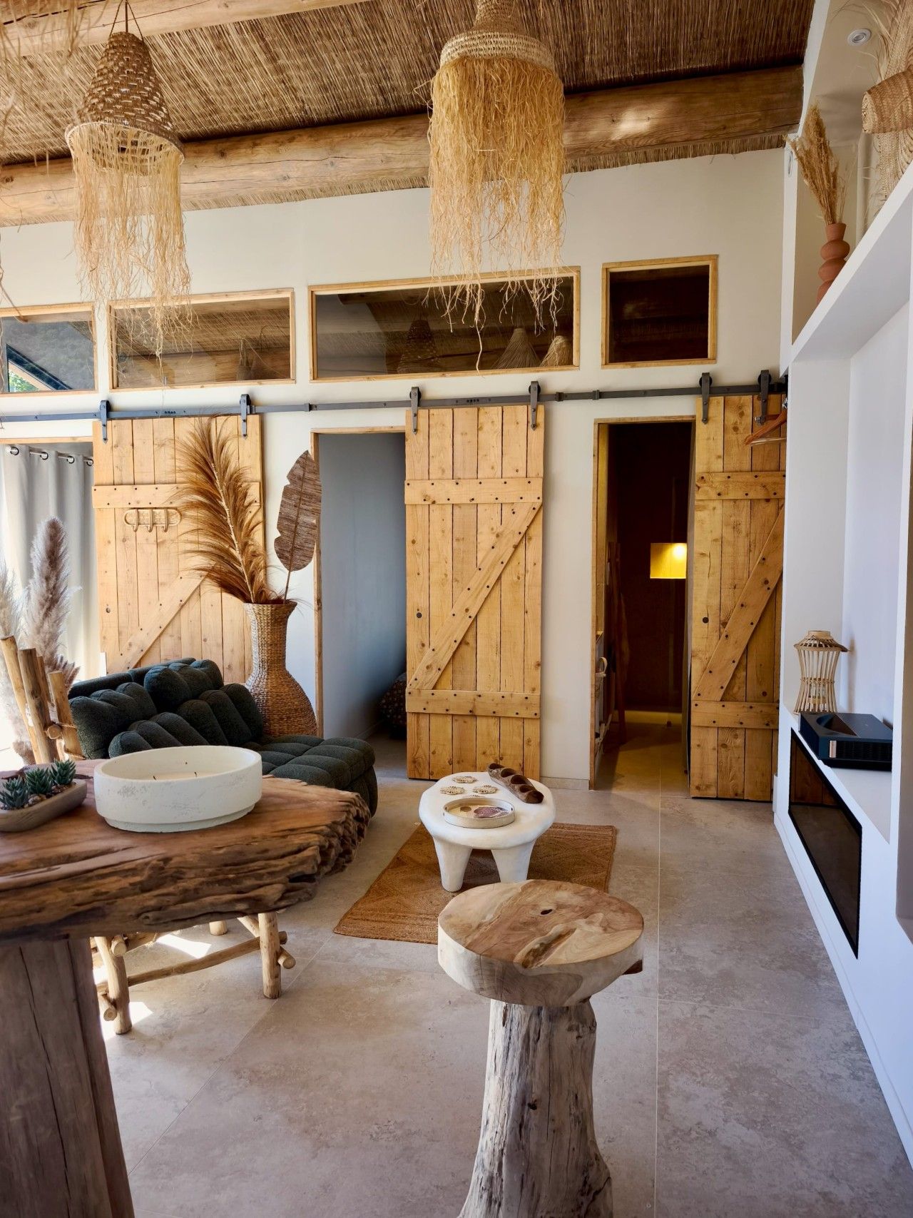 Un intérieur rustique avec des murs en bois, un plafond de chaume et une grande porte coulissante de grange.