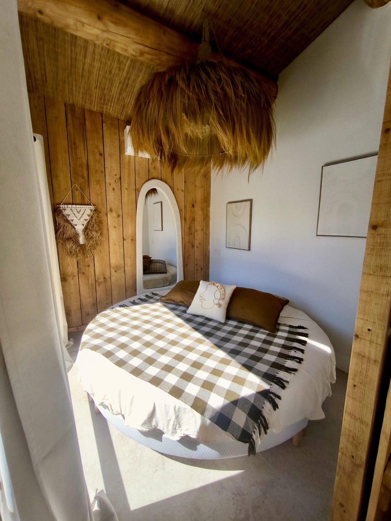 Une pièce comprenant un lit, un plafond recouvert de chaume, des murs en bois et un petit coin salon.