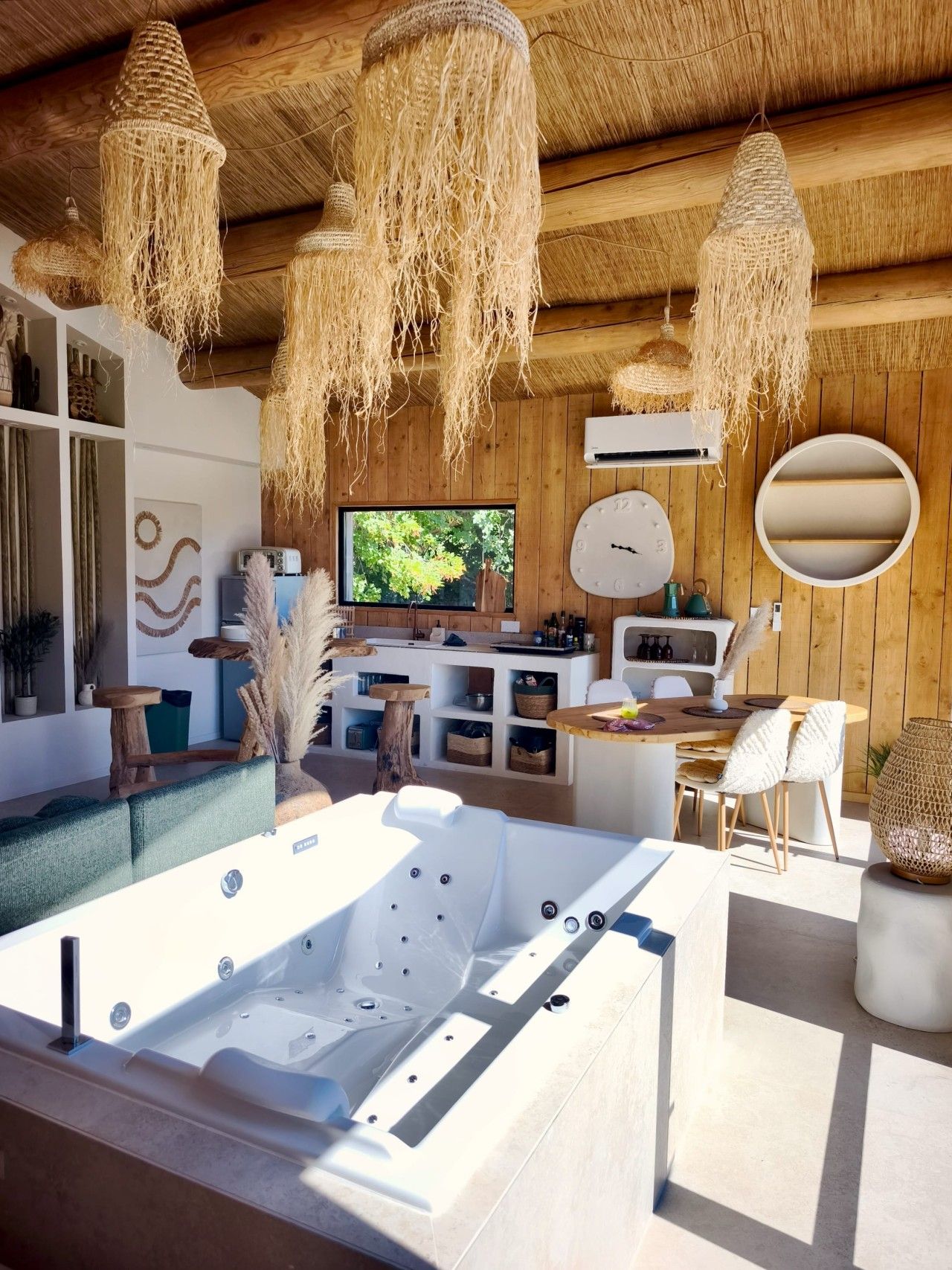 Een modern interieur met een houten plafond, een grote televisie, een ronde spiegel en een whirlpool.