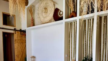 Een landelijk interieur met een houten eettafel, een open haard en een hangende geweven lamp.