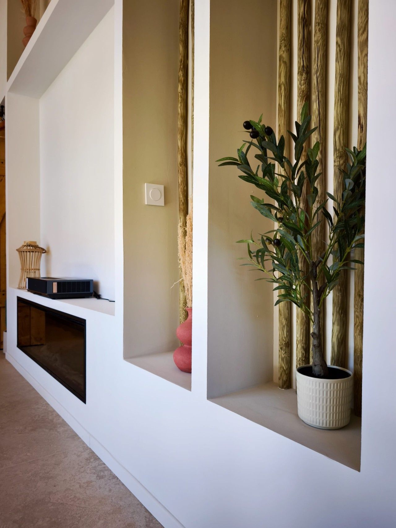 Interior moderno com estantes embutidas, um vaso de planta e um vaso decorativo.
