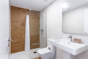 A modern bathroom with a wooden wall, a glass shower enclosure, a white sink, and a toilet. - Luxury Seaview Isea 2231 by Casasol (Torrox)