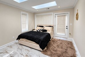 Ein Schlafzimmer mit einem Bett, einem flauschigen Teppich, einem Oberlicht und einer Tür mit einem goldenen Griff.