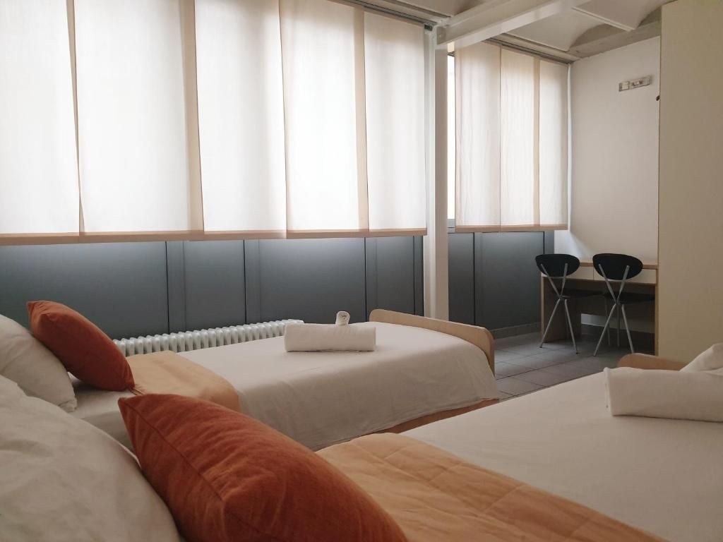 Een hotelkamer met twee bedden, een bureau en een stoel.