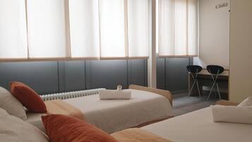 Een hotelkamer met twee bedden, een bureau en een stoel.