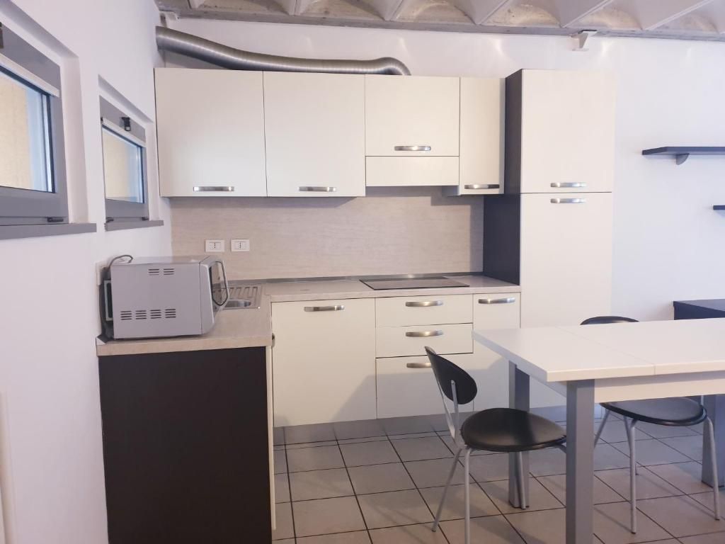 Een compacte keuken met witte kastjes, een klein aanrecht en een eethoek met een tafel en stoelen.