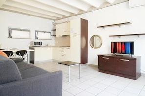 Una cocina moderna con armarios blancos, microondas y un comedor con mesa y sillas.