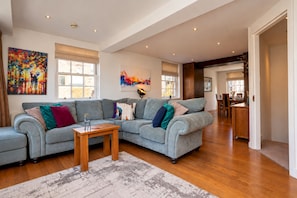 A spacious living area with a grey sectional sofa, a wooden coffee table, and a patterned rug. - Family Home near Angel with Terrace - Pass the Keys (London)