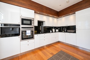 A modern kitchen with white cabinetry, a black countertop, and wooden flooring. - Family Home near Angel with Terrace - Pass the Keys (London)