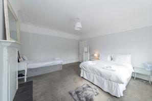 A minimalist bedroom with a large bed, bedside tables, a mirror, and a small rug. - Private flat Near Shops & Thames Riverside - Pass the Keys (Reading)