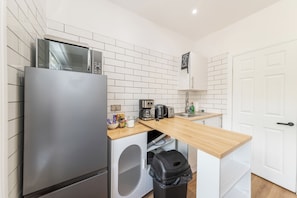 A compact kitchen with a stainless steel refrigerator, a washing machine, a coffee maker, and a toaster. - Private flat Near Shops & Thames Riverside - Pass the Keys (Reading)