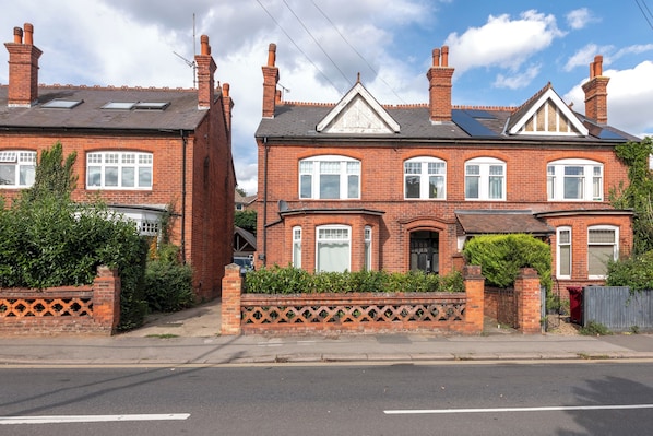 A row of red brick houses with pitched roofs, front gardens, and a clear sky. - Private flat Near Shops & Thames Riverside - Pass the Keys (Reading)