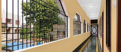 Un pasillo con vistas a una piscina y vegetación.