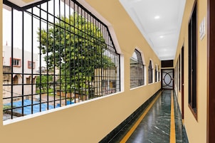 A corridor with a view of a pool and greenery outside.
