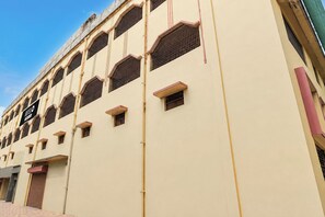 Een meerhoog hotel met een beige gevel, meerdere ramen met metalen tralies en een bord dat een hotel aangeeft.