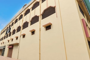 A multi-story hotel with a beige facade, multiple windows with metal grilles, and a sign indicating a hotel.