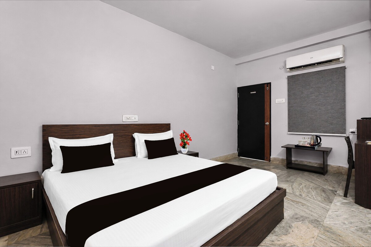 Habitación de hotel con cama, mesita de noche, aire acondicionado, puerta y ventana.