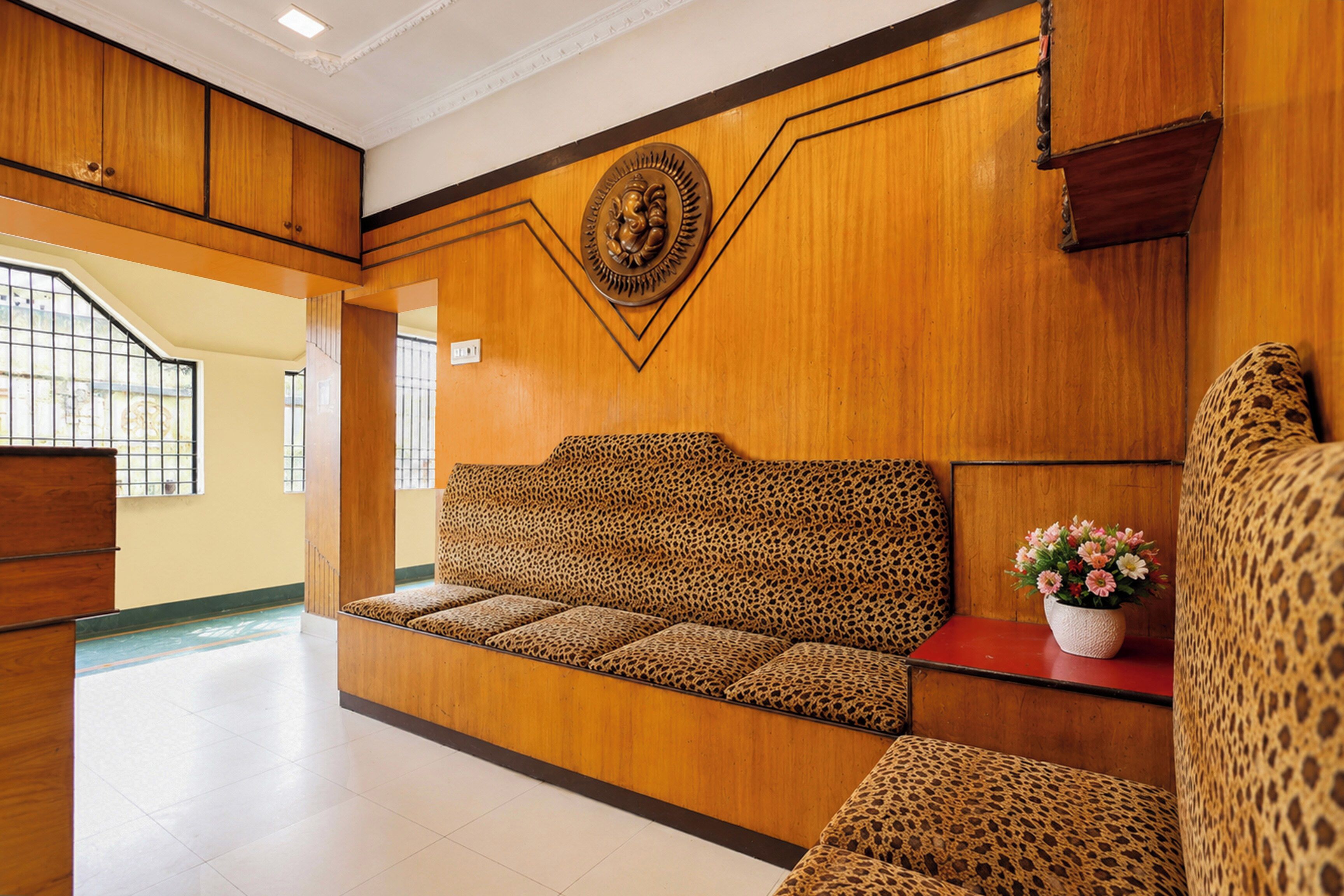 Un espace d’accueil avec un comptoir de réception en bois, un canapé agrémenté d’un coussin à motifs léopard et un élément décoratif mural.