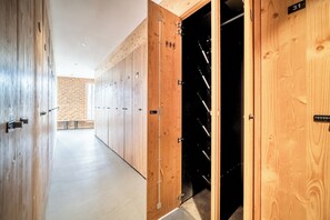 A hallway with wooden lockers and a black door with ski equipment. - Nanook – Ski-in/Ski-out | Pool | Gym | Alpe d’Huez (Huez)