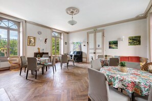 A spacious dining area with wooden flooring, multiple dining tables, and chairs.