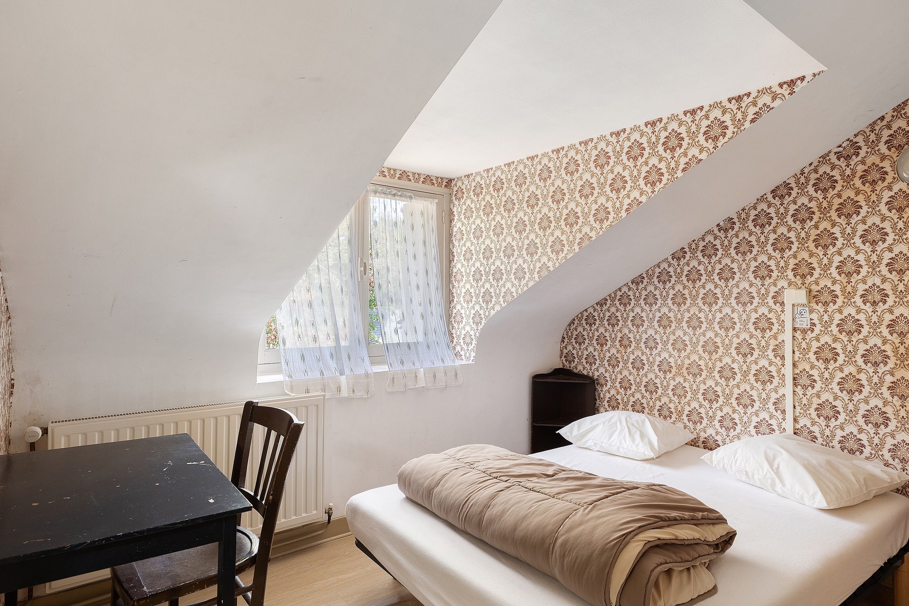 Un dormitorio con cama, una mesa y una silla.