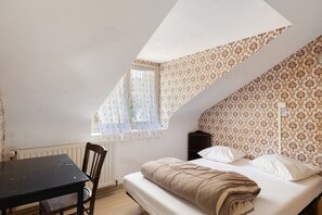 A bedroom with a bed, a table, and a chair.