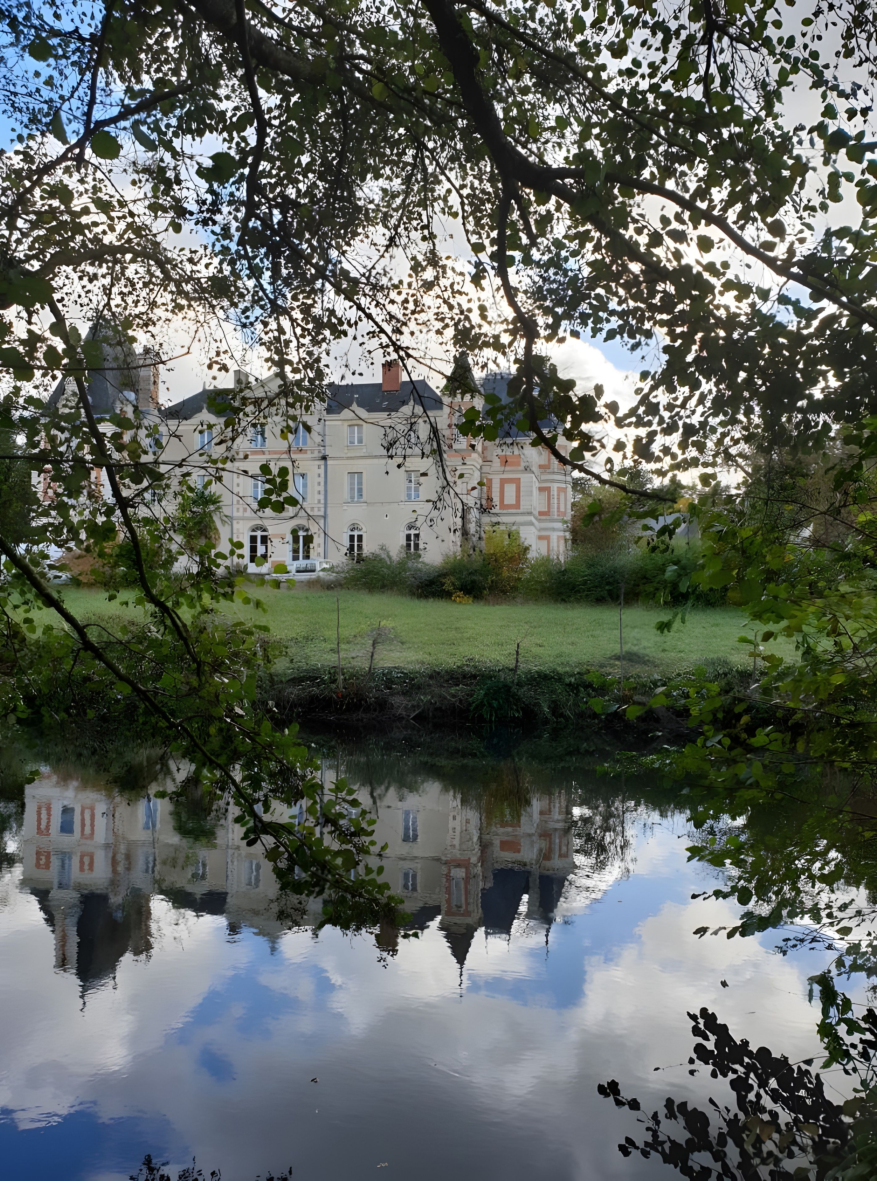 A building with a reflection in a calm body of water, surrounded by greenery.